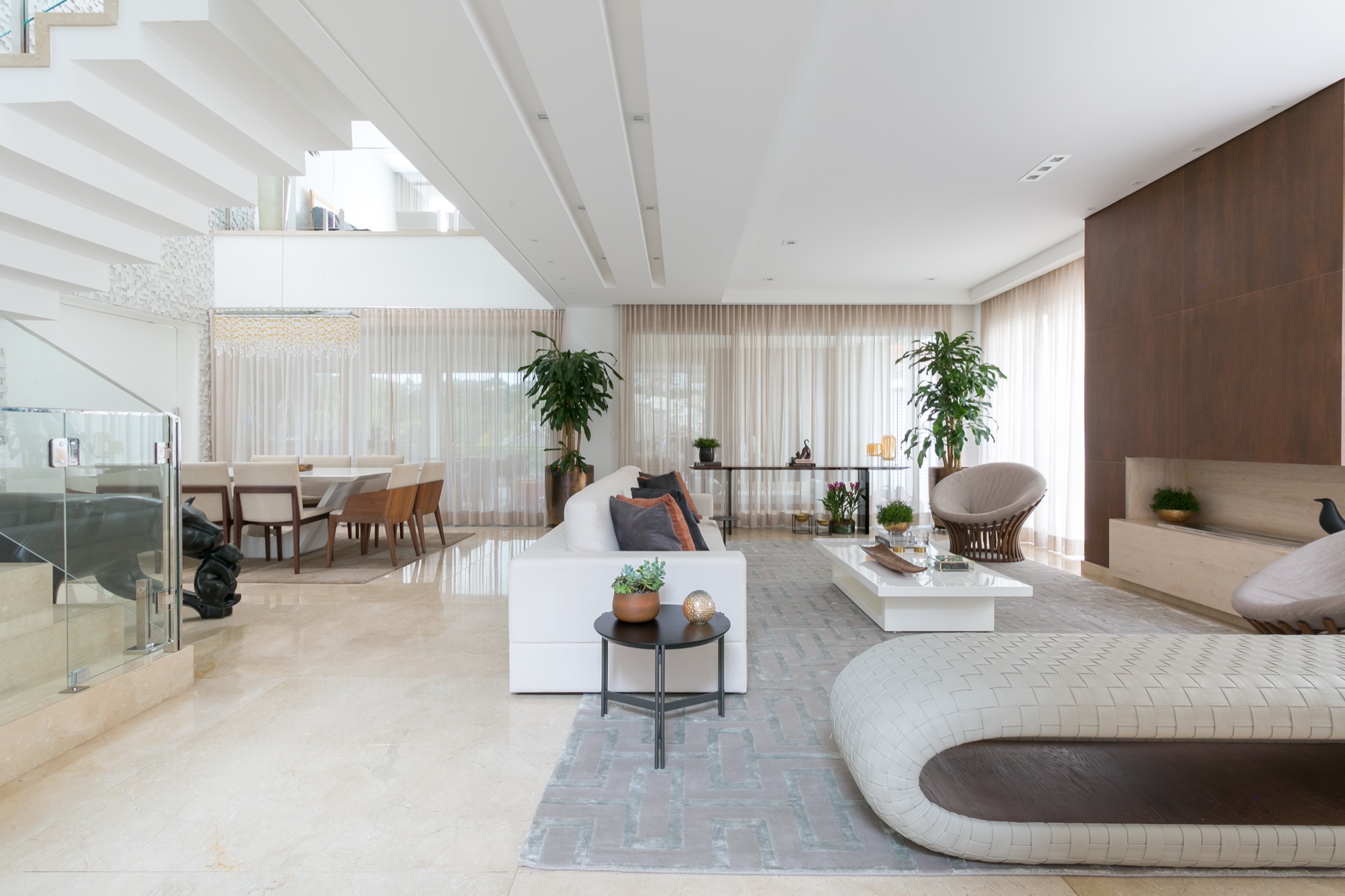 Living integrado da Casa Han: pé-direito duplo, sofá branco, painel de madeira e jantar ao fundo