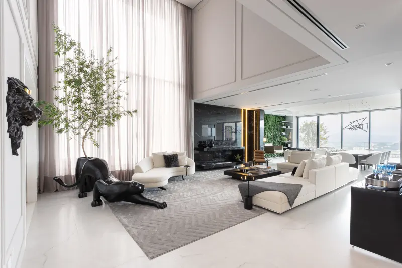 Living de pé-direito duplo todo branco com cortinas altíssimas e árvore interna
