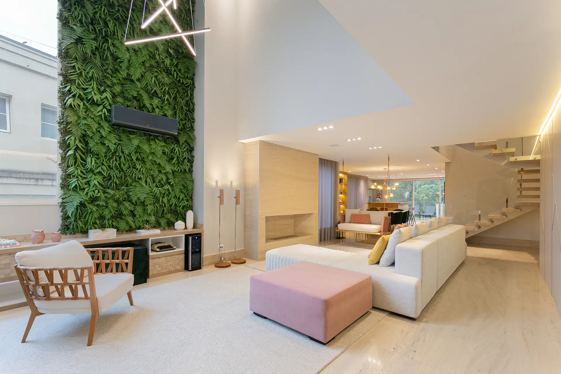 Living de pé-direito duplo da Casa EC, com jardim vertical e paleta pastel