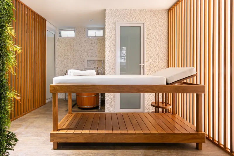 Sala de massagem entre dois painéis ripados de madeira clara